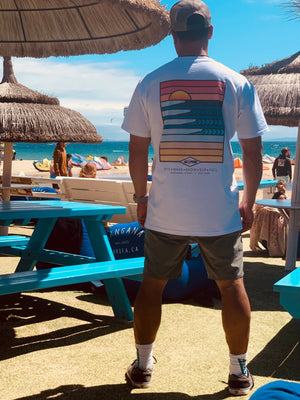 Man wearing a white t-shirt with a colorful design on a beach setting