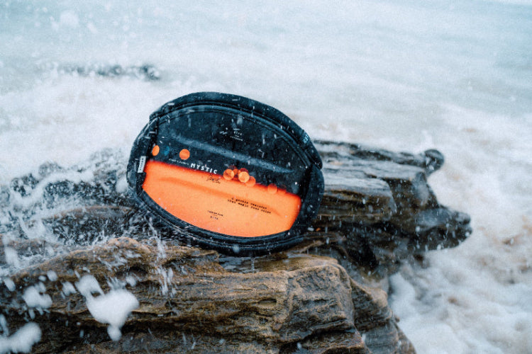 Orange and black KITESURFING HARNESS on a ROCK BY THE SEA 