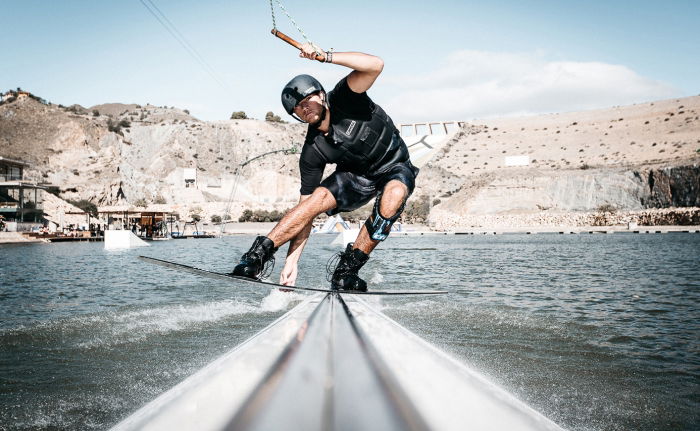 Peacock brothers wakeboarding on a lake with mountains in the background