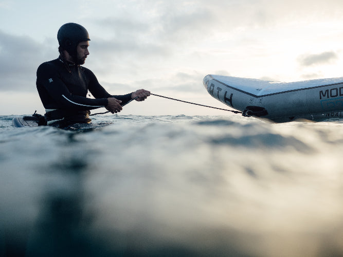 Person in a wetsuit in the water learning to wing foil